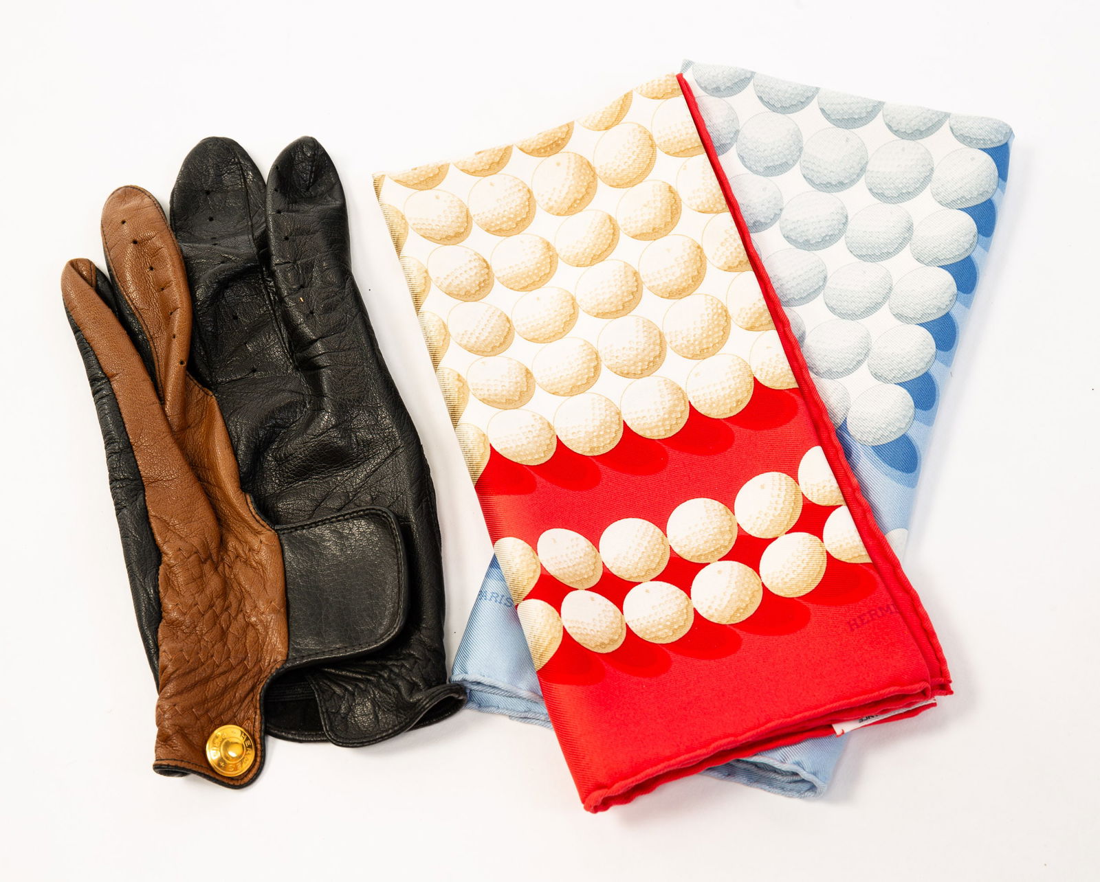 GROUP OF GOLF-THEMED ITEMS BY HERMES.: Men's black and brown leather golf glove, size 8; two silk pocket squares (one red and one baby blue) with all over golf ball pattern, 16" square. All in original boxes.