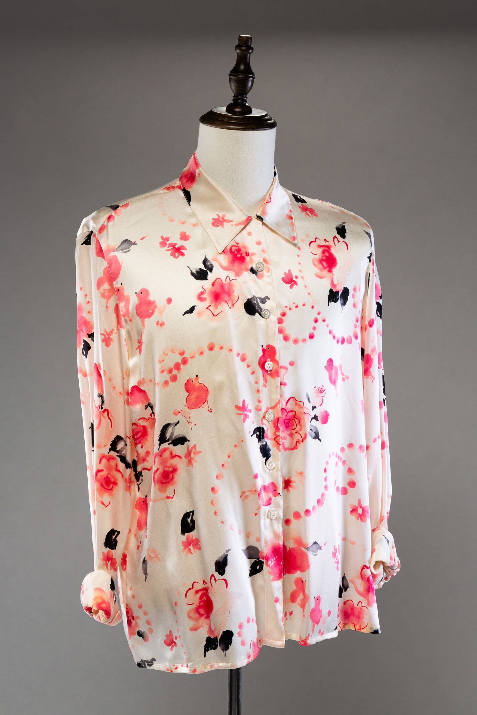TWO ESCADA SILK BLOUSES.: German. Silk. Size 44. Black filed with button stripes. White field with pink flowers and French poodles. Light wear.