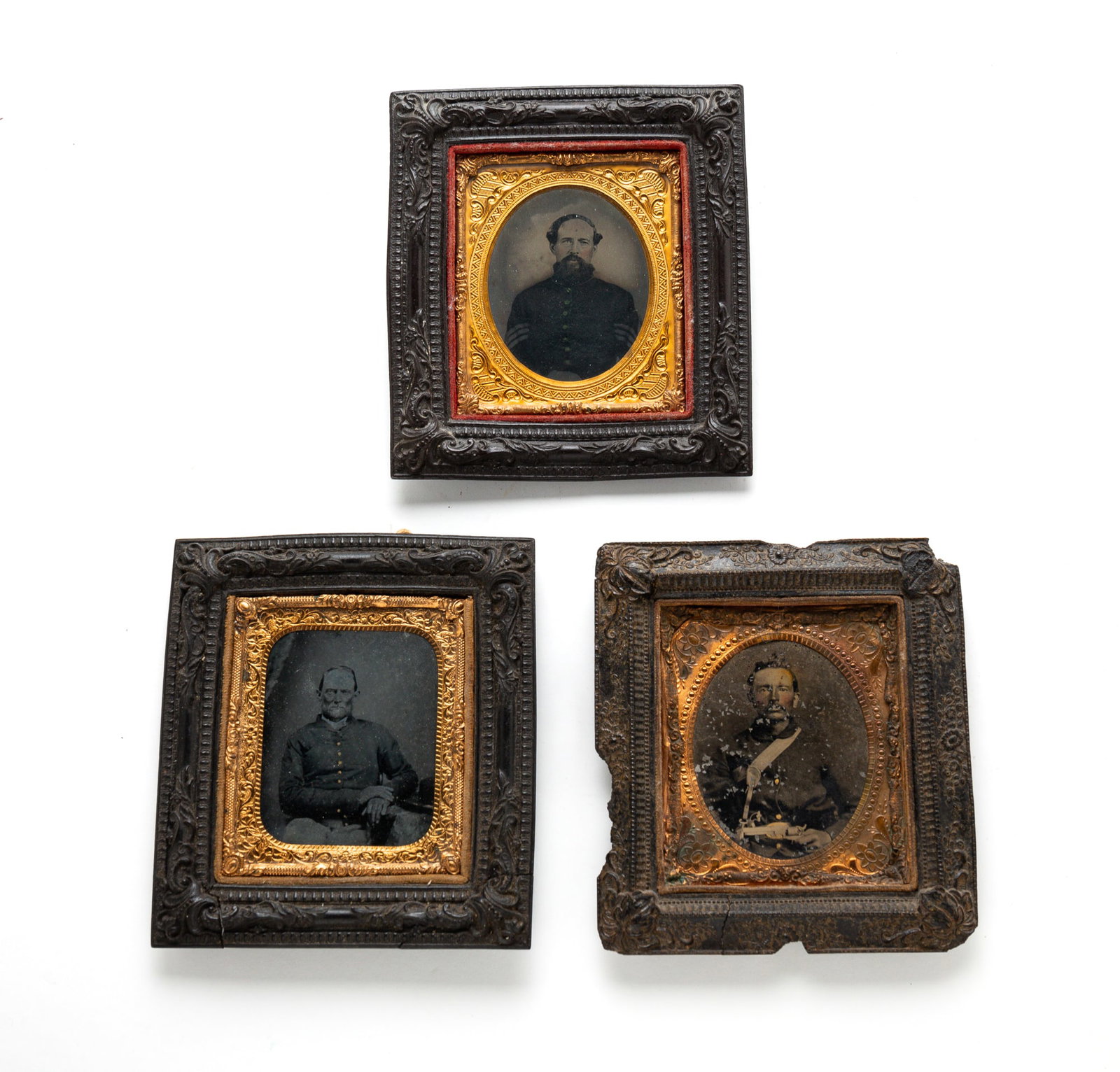 THREE SIXTH PLATE FRAMED CIVIL WAR IMAGES.: American, third quarter 19th Century. Tintypes. Three seated, uniformed men, one holding a revolver. Hand-colored highlights. In Gutta Percha frames. Varying wear and loss.