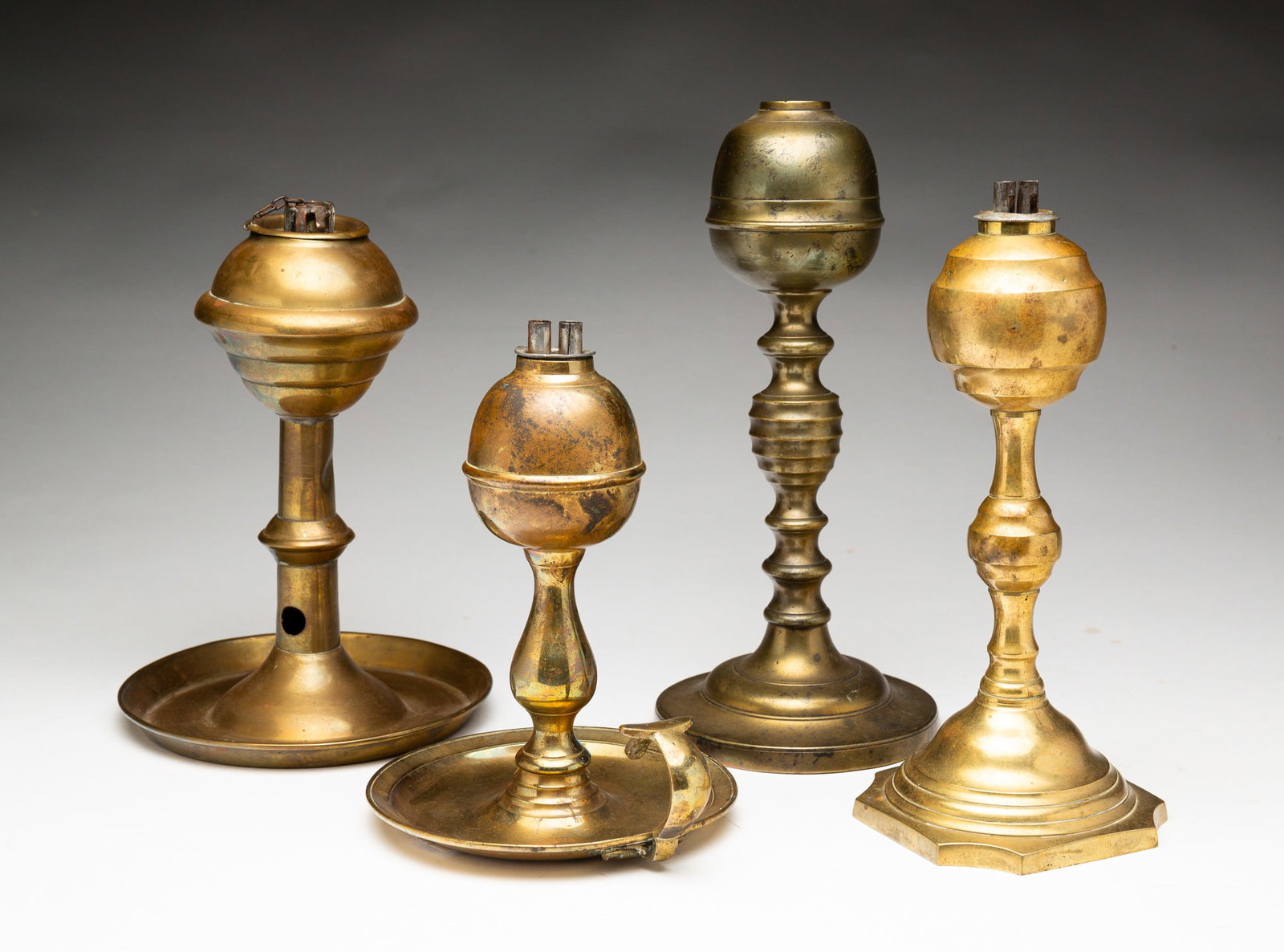 GROUP OF WHALE OIL LAMPS.: GROUP OF WHALE OIL LAMPS. American, mid-19th Century. Brass. Four lamps. One with attached underplate marked S. Davis with attached wick pick. Dents and wear. 7.3"h. Round base lamp. Missing burner an