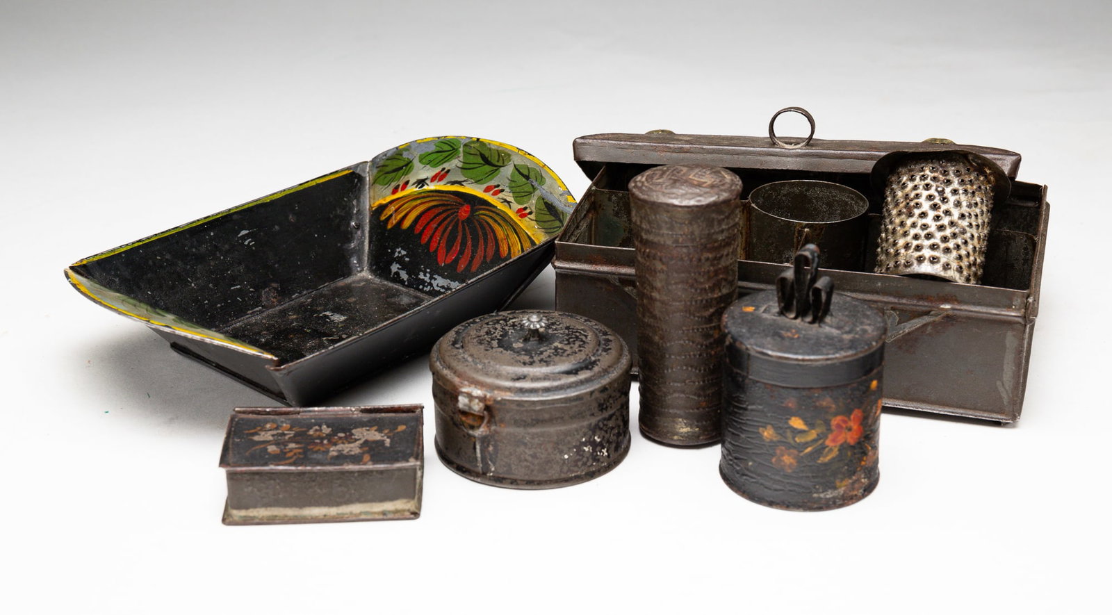 SIX PIECES OF TIN.: American, second half 19th Century. Miniature tole apple bowl with flora and foliate decoration. Paint loss and wear. 1.5"h. 4"w. 3.75"I. A tole cylindrical tim with looped finial, 2.5'' h. A tole boo