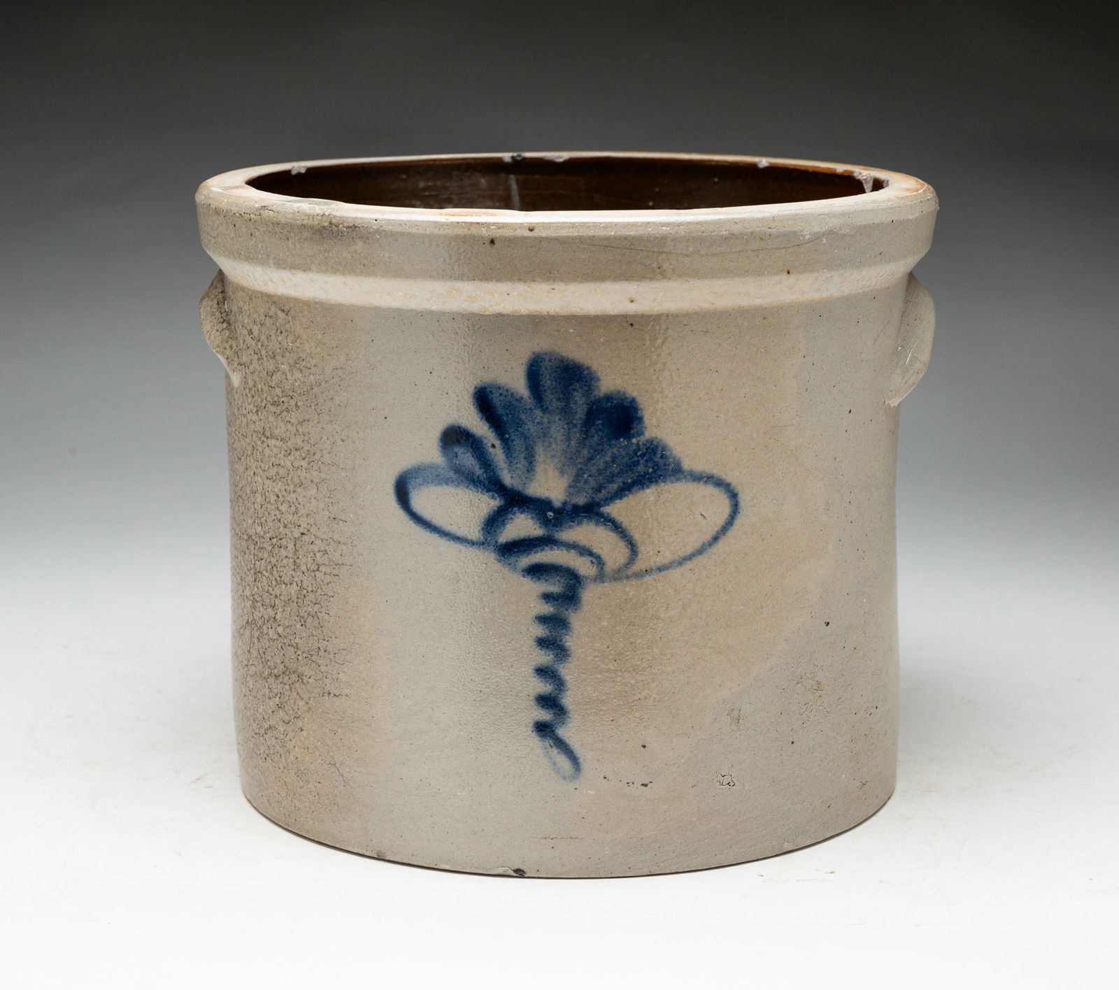 DECORATED STONEWARE CROCK.: American, second half 19th Century. Flourish with a bee stinger in cobalt. Small applied handles. Surface wear, chips to edges. 6.9"h.