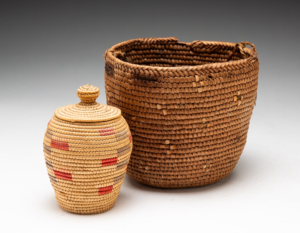 TWO BASKETS.: American (one Alaskan and one Salish), first half 20th Century. Carrying basket with crosses decoration and braided handle. 5.5"h. 5.5"dia. Lidded basket with red and green design. 4.5"h. 2.5"dia.We d