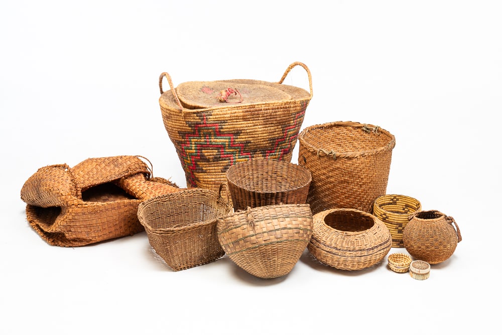 TWELVE BASKETS.: Of varying tribes including Pima, Papago, cedar bark Alaska, etc. In varying shapes, sizes, and dates. Red, green, and black decorated two handled basket 17"h. 25"w. 21"l.We do not guarantee tribal at