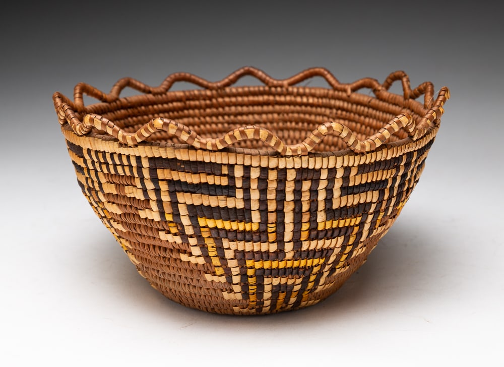 SMALL NORTHWEST COAST BASKET.: Klickitat, first quarter 20th Century. Yellow polychrome and scalloped serpentine cap with geometric designs running throughout. Fine condition. 4"h. 8.5"dia.We do not guarantee tribal attributions fo