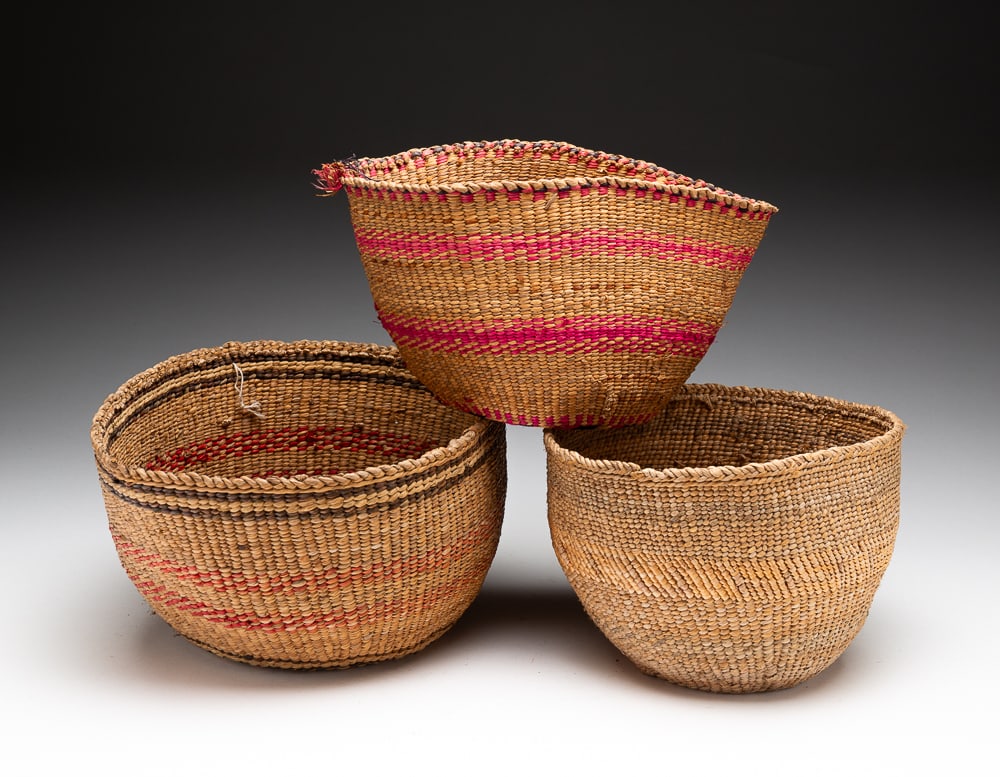 THREE NORTHWEST COAST BASKETS.: First half 20th Century. Horizontal black band under rim with two red diagonal design stripes and green polychrome on base. Overall good condition. 5.5"h. 9"dia. Berry basket with fuschia band decorat