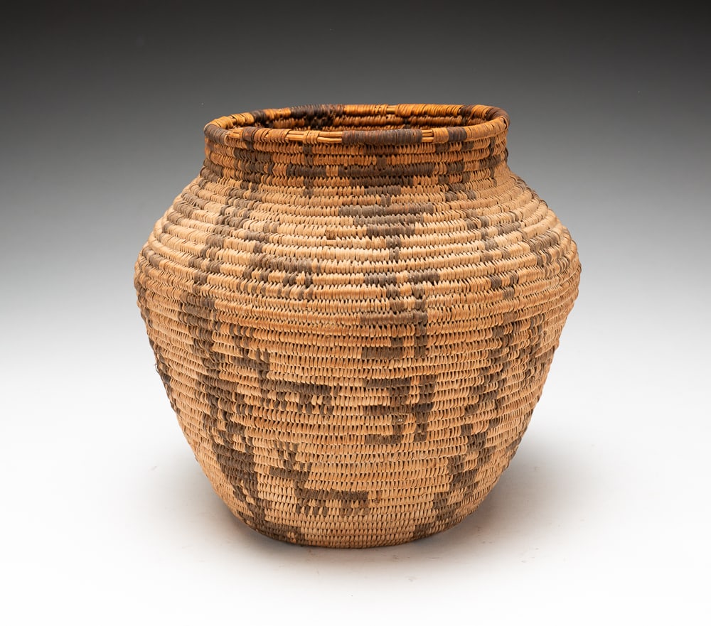 APACHE OLLA BASKET.: Apache, circa 1900. Motifs of deer and figural men running throughout against geometric designs. Rim wear with a couple of breaks. 7.5"h. 8"dia.We do not guarantee tribal attributions for American Ind
