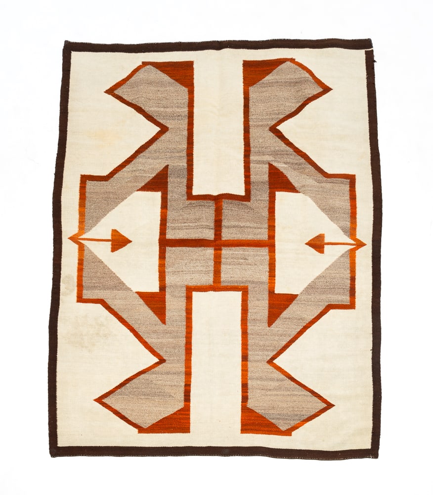 NAVAJO RUG.: Navajo, circa 1930. Ivory and grey field with burnt orange and brown pattern depicting cross and arrows. Minor edge damage, needs cleaning, numerous stains that go through both sides. 50"w. 88"l.We do