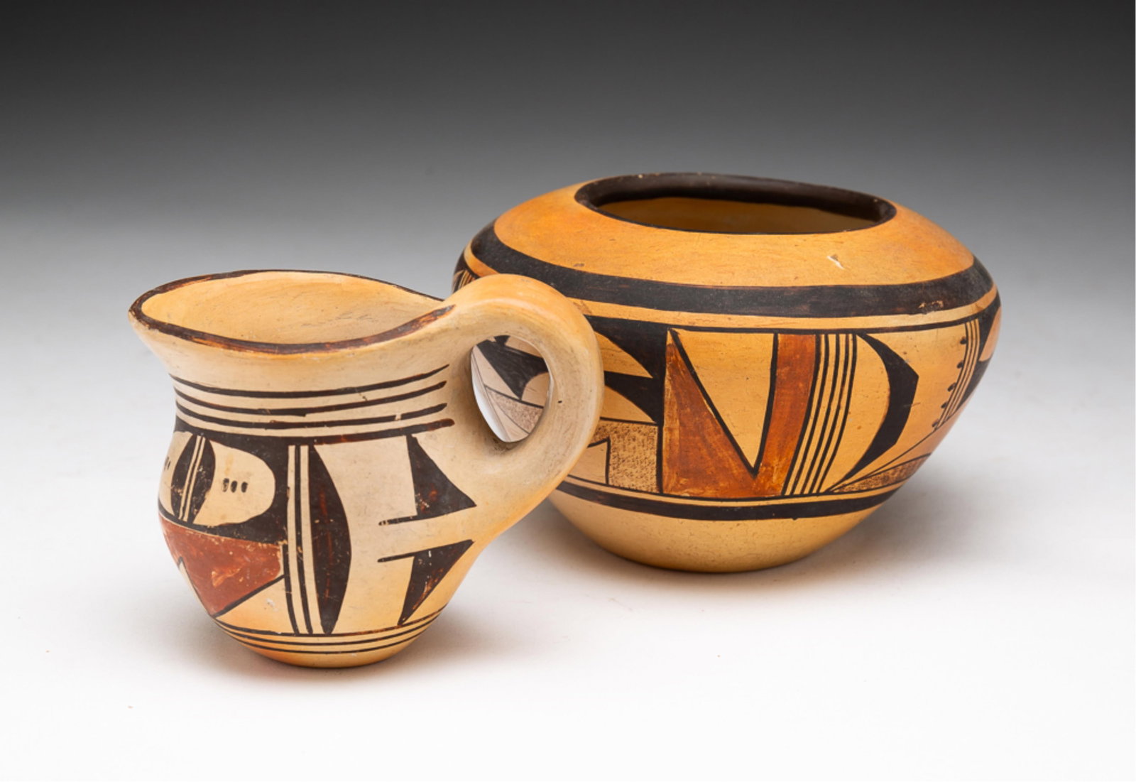 TWO SMALL HOPI POTTERY VESSELS.: Hopi, first half 20th Century. Comprising a pottery jar and a creamer with classic Hopi designs of frogs and corn signatures on the underside of each vessel. Overall good condition with some wear. No 