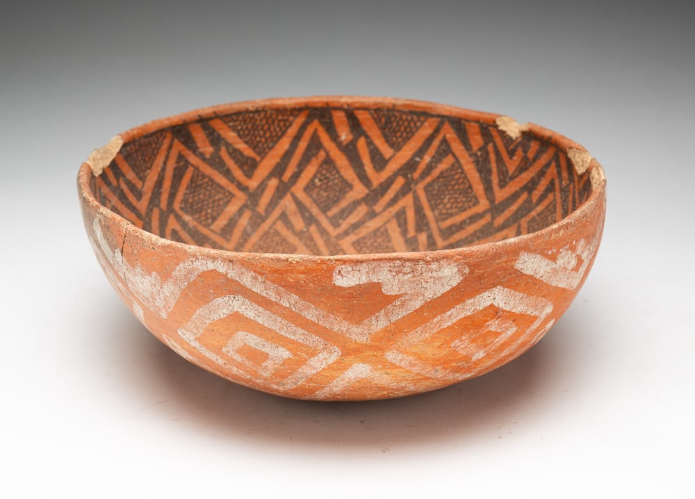ARCHAIC FOUR MILE POTTERY BOWL.: 1400 to 1600 A.D. Asymmetrical design running throughout. Overall good condition with chips to rim and cracks. 4"h. 10"dia.We do not guarantee tribal attributions for American Indian / First Nations i
