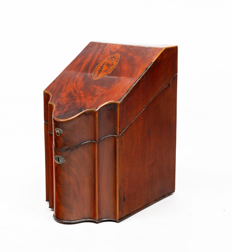 INLAID KNIFE BOX.: English, circa 1800. Mahogany. Slanted lid, shaped front, beaded edges, string, shell and star inlays. Interior retains fitted cutlery holder. Refinished, some age splits and missing inlay. 15"h. 9"w.