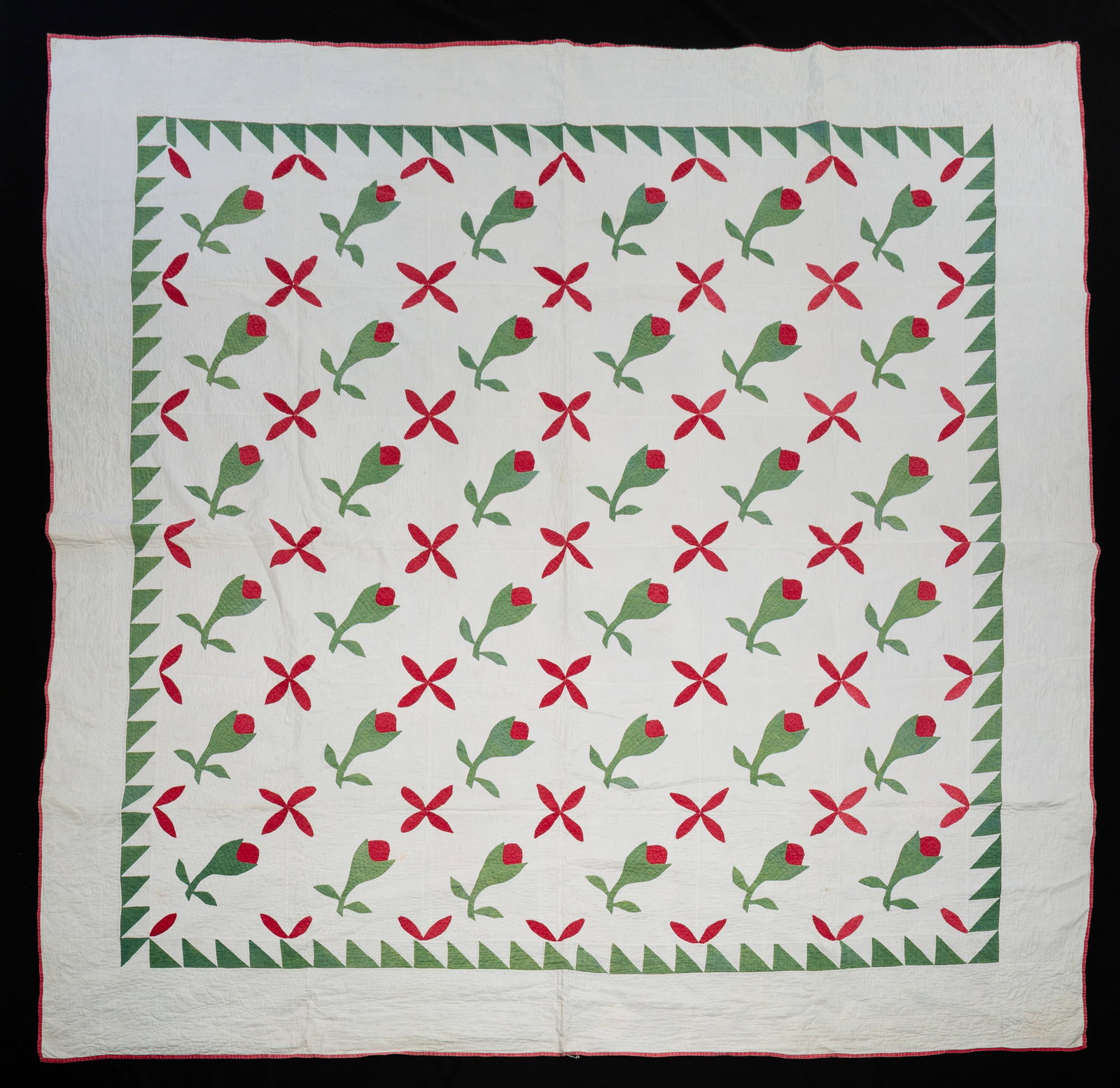 APPLIQUED "ROSEBUD" QUILT.: American, mid-19th Century. Red and green on white ground. Green and white inner border of half-square triangles. A few small light stains, binding lightened from wear. 81.25"w. 82"l.