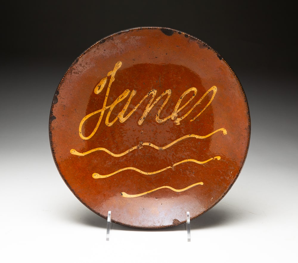 REDWARE SLIP DECORATED PIE PLATE.: American, mid-19th Century. Coggled rim, "James" to center. Wear and chips. 12.25"dia.