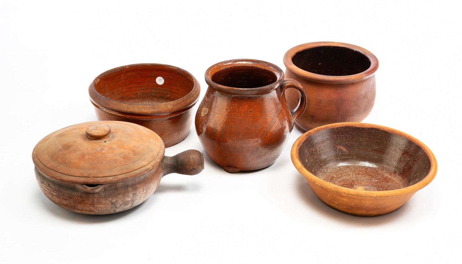 FIVE PIECES OF REDWARE.: American and European, mid-19th Century. A lidded pan with pouring spout. Chips and cracks. 6"h. 12.5"w. A pan with canted sides. Chips and wear, 3.25"h. 12"dia. A bowl with shaped lip. Glaze wear, ch