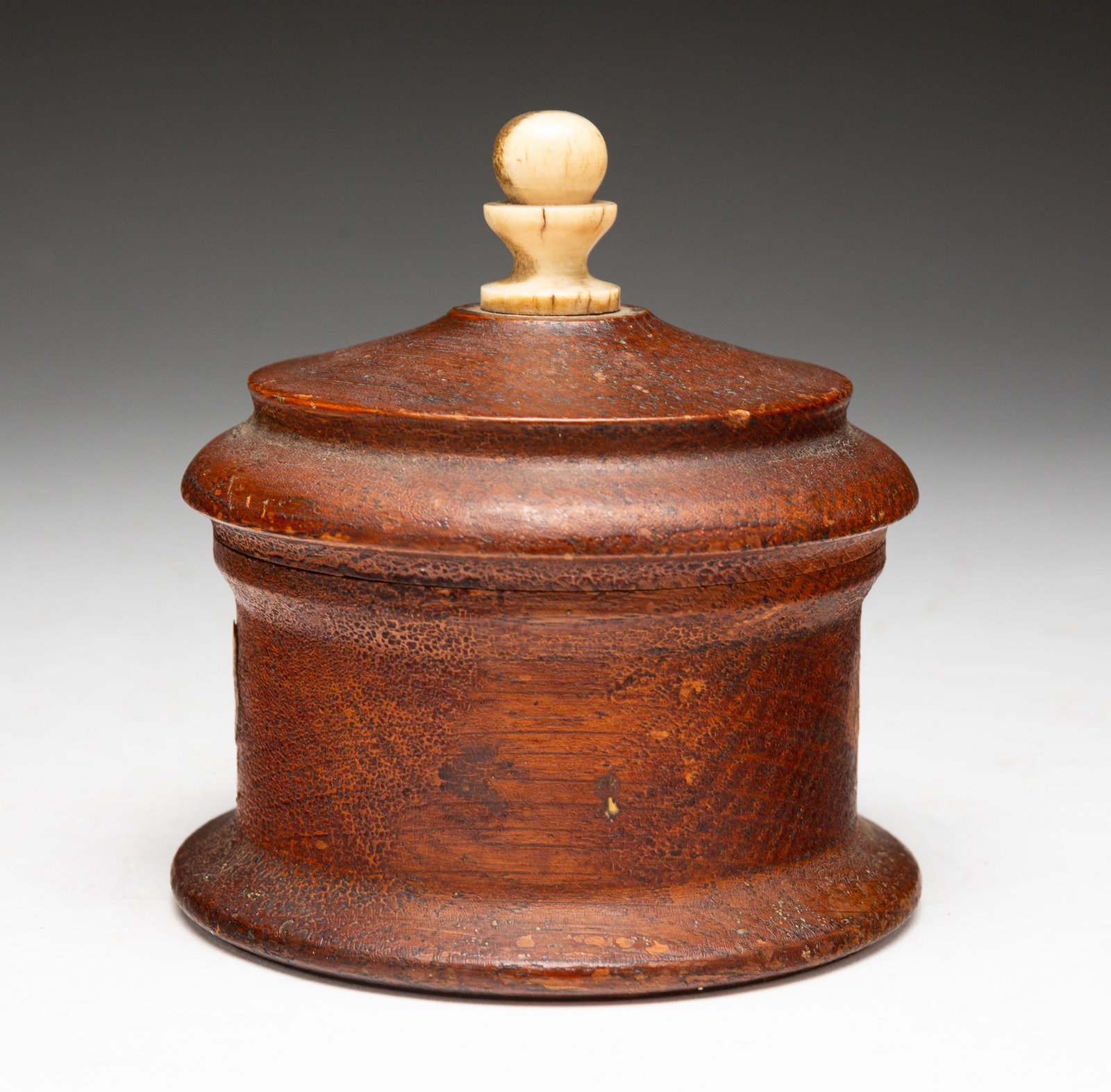 TREENWARE LIDDED JAR WITH DEER HORN FINIAL.: American, 19th Century. Turned wood with applied cherub decoration and threaded lid with deer horn finial. With note on bottom reading "Made by Uncle Mackin. [illegible] The top made from deer horns."