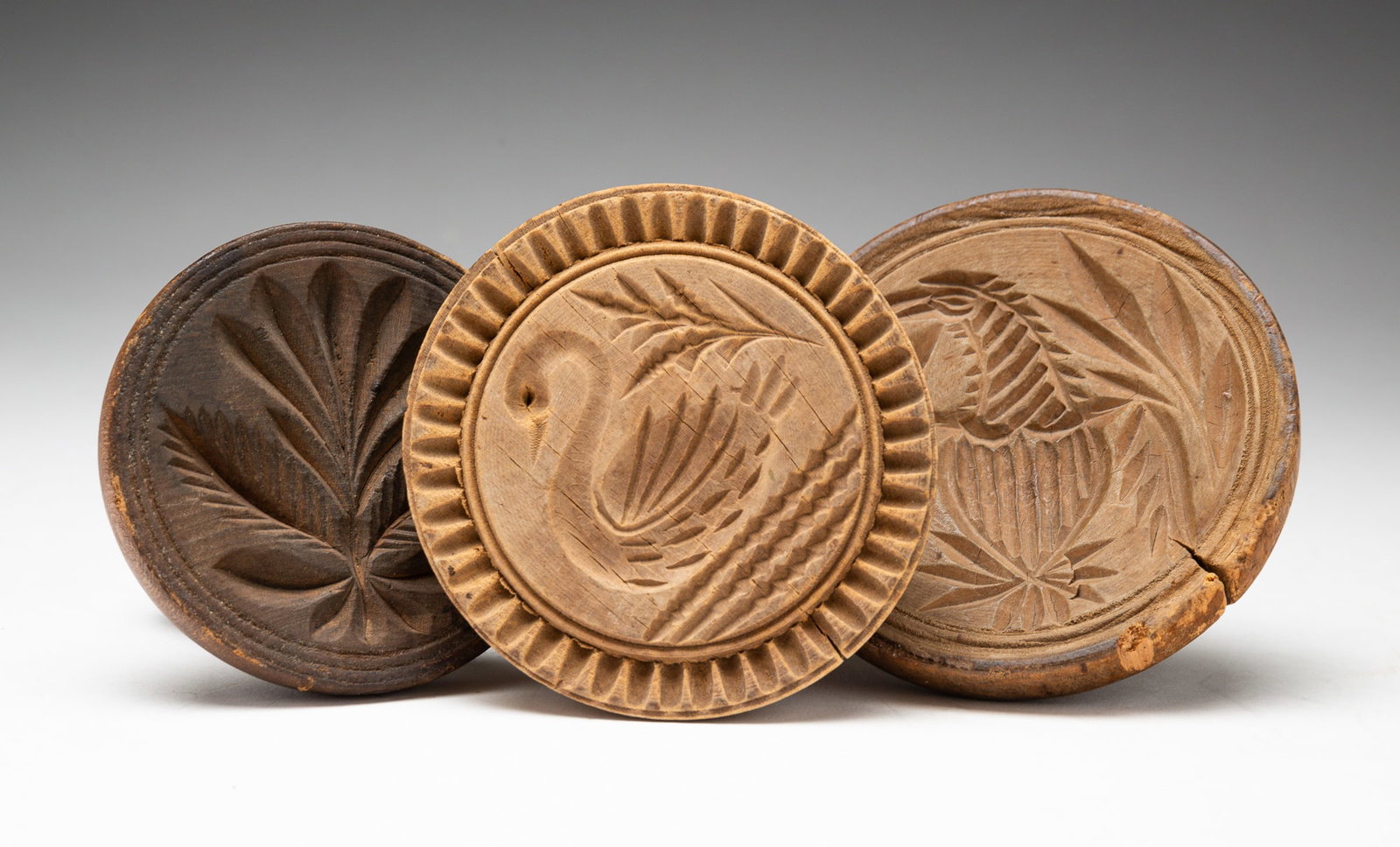 THREE BUTTER STAMPS.: American, 19th century. Consisting of an eagle and shield stamp, a swan stamp, and a floral stamp. All with chips and cracks. Tallest 6.25"h.