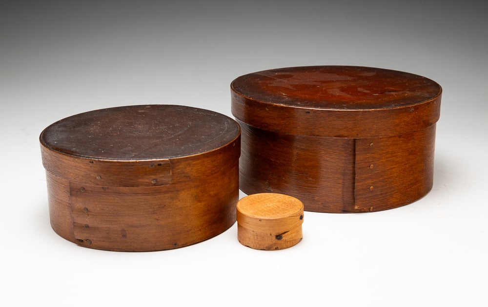 THREE BENTWOOD PANTRY BOXES.: American, second half 19th Century. Pine. The larger two have lap joints, copper tacks and old worn finishes, 3.75"h. 9.75"dia. And 3"h. 6.5"dia. And smallest with Harvard joints tacks. 12.5"h. 2"dia.