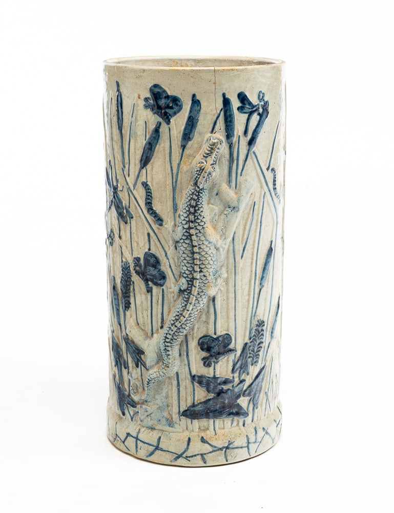WHITE'S STONEWARE UMBRELLA STAND.: American (Utica, New York), late-19th Century. Cylindrical shape with relief molded alligator, cattails and insects. Salt glaze with cobalt highlight. Cracks and repairs. 20"h. 9.5"dia.
