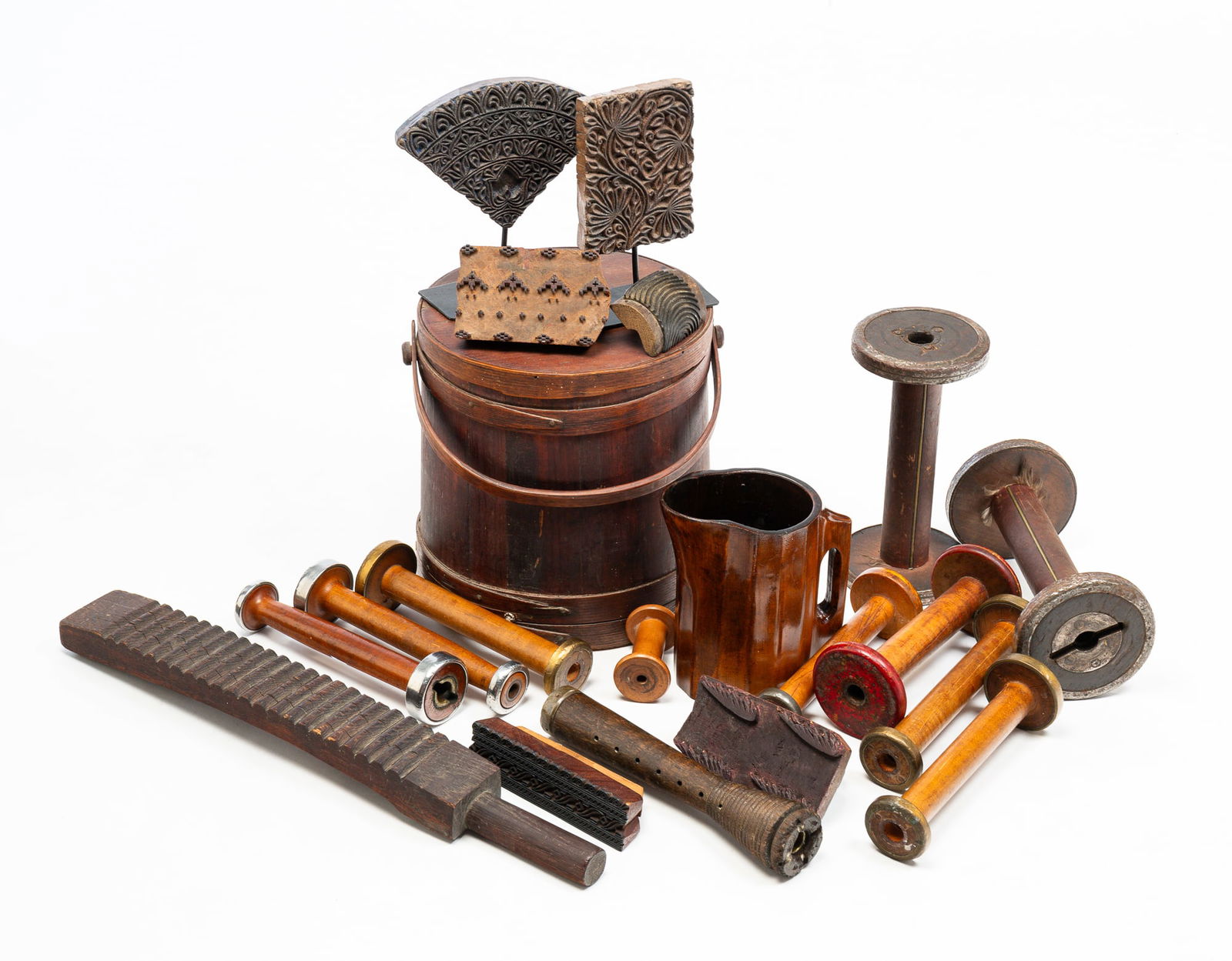 INTERNATIONAL WOODEN WARE GROUP.: 19th Century. A stave constructed firkin with finger joint bands and bail handle, spools in various sizes, wash board, noggin and batik printing blocks. Wear and loss.