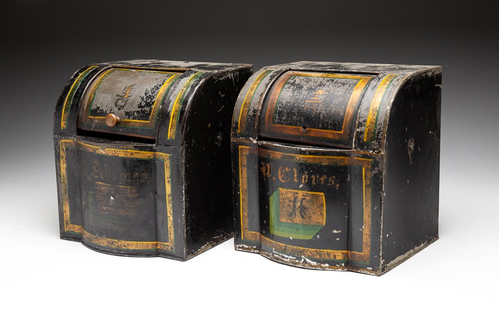 TWO TOLE PAINTED SPICE CONTAINERS.: American, second half 19th Century. Cylinder roll top containers. Allspice and Cloves. Worn paint and one missing knob. 8"h. 7.5"w. 7"d.