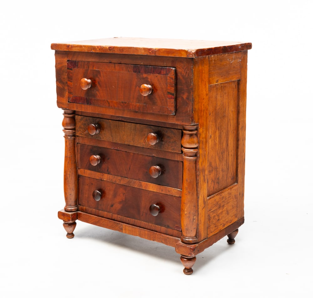 TRANSITIONAL MINIATURE CHEST.: American, second quarter 19th Century. Pine with mahogany veneer. Sheraton to Empire. Paneled ends, half turned pilasters, turned legs, four dovetailed drawers, refinished with some pieced veneer repa