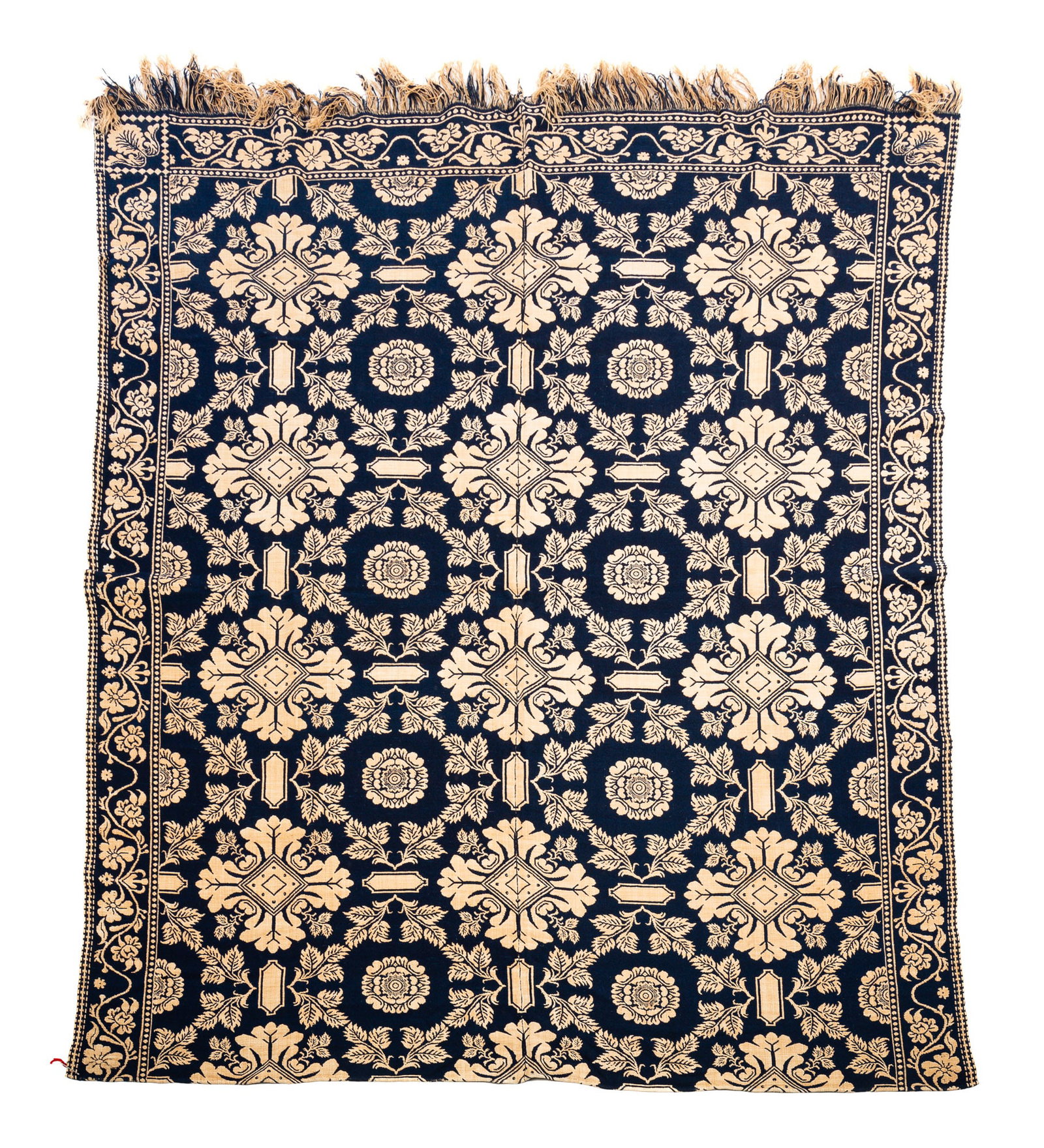 BLUE AND NATURAL JACQUARD COVERLET.: American, mid-19th Century. Blue and natural. Central field with flowers and stylized medallions; vining floral border. Winged shell corner block often of Eastern Indiana origin. Some discoloration bu