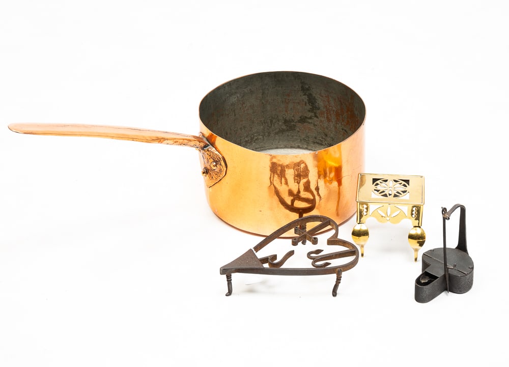 GROUP OF METAL HOUSEWARES.: American, 19th Century. Comprising a copper pot, a mini brass footman, a forged iron trivet and a forged iron betty lamp. Copper pan 5.5"h.
