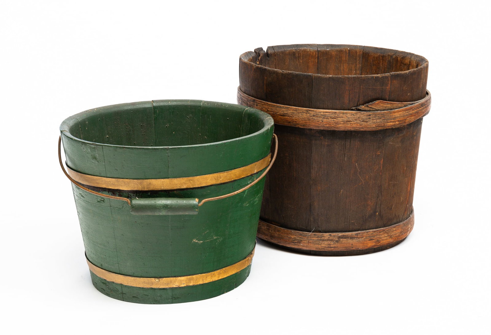 TWO STAVE CONSTRUCTED BUCKETS.: American, second half 19th Century. Pine. One is in natural finish with oak hoops. Wear and edge loss. 11.5"h. 12.5"dia. The second has a wire bale handle, metal hoops and green and gold repaint. 9"h.