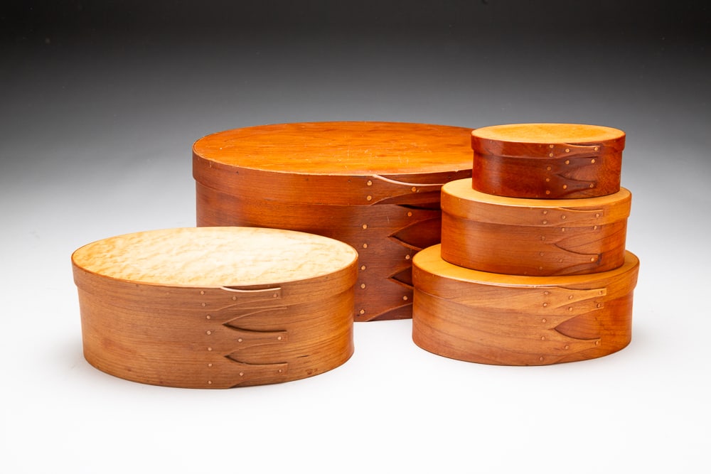 FIVE SHAKER STYLE BENTWOOD BOXES.: 20th Century. Made of various woods in graduating sizes, with finger joints and copper tacks. The smallest three with labels reading "SHAKER BOX MAKER Brian Bergsten Springboro, Ohio" on bottom. The l