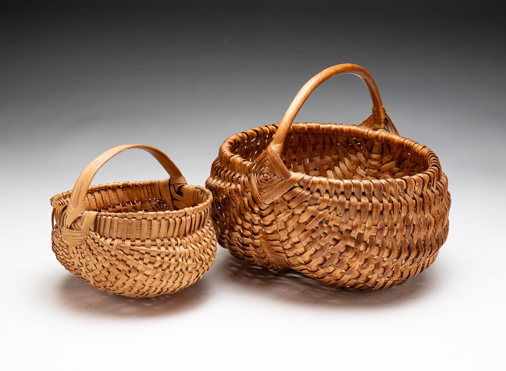 TWO SMALL WOVEN SPLINT BASKETS.: Early-20th Century. Each with a handle. Wear and staining to larger basket, spots of red paint on underside of smaller basket. Larger 7"h.