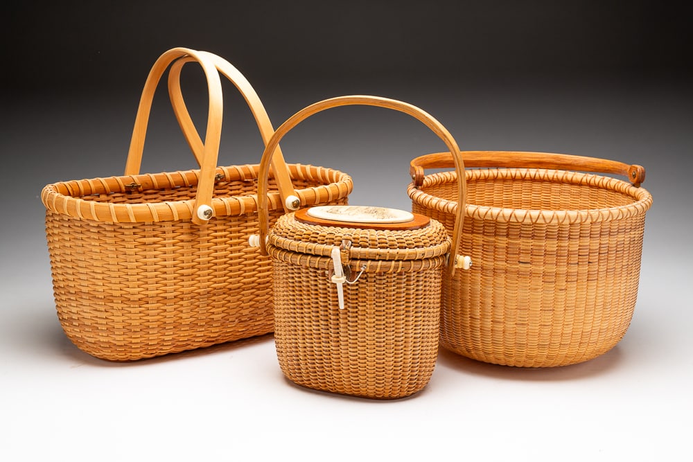 THREE NANTUCKET LIGHTSHIP BASKETS.: American, second half 20th Century. Round basket with swing handle and carved wood whale detail on interior base, signed "Norbert A. Hala" with a 1989 penny on underside. With handle 12"h. Oval lidded