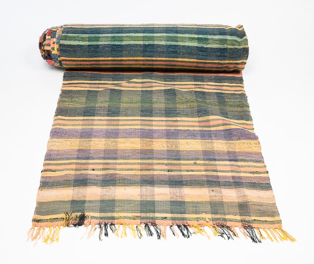 MONUMENTAL RAG RUG RUNNER.: American, first half 20th Century. Multi-colored striped plaid. Fringe to either end. Wear, staining and repairs. Approximately 61'l. 3'5"w.