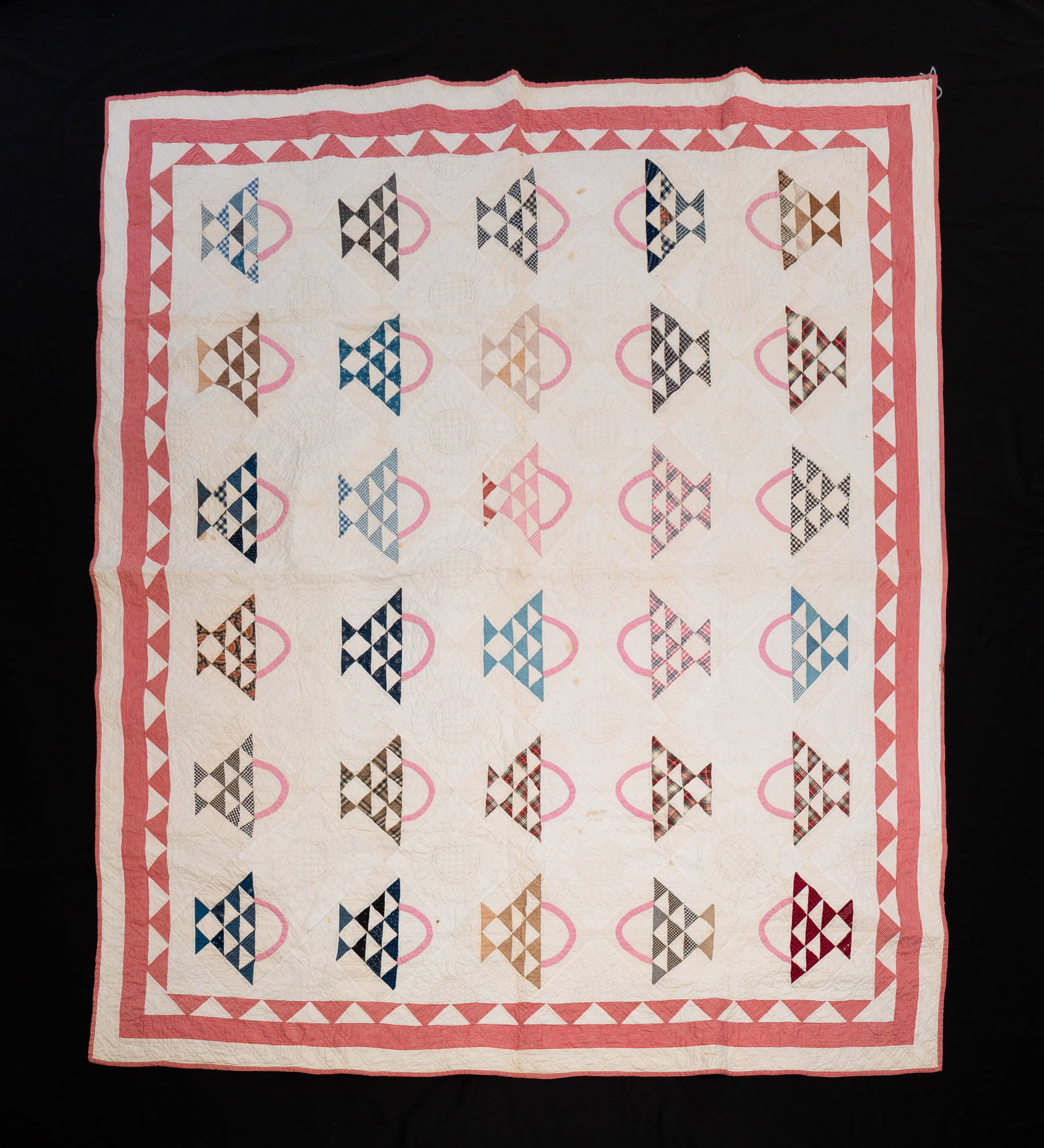PIECEWORK AND APPLIQUE QUILT IN FLOWER BASKET PATTERN.: American, 20th Century. Multicolored pieced baskets with pink appliqued handles on an ivory quilted ground within a red border and edges bound in red. Staining and discoloration. 80"w. 164"l