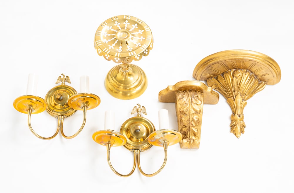 FIVE DECORATIVE PIECES.: Late-19th and early-20th Centuries. Two gilt wooden wall shelves, 7.5"h. And 9.5"h. A pair of brass wall sconces with eagle accents. And a brass pierced top trivet, 9.25"h.