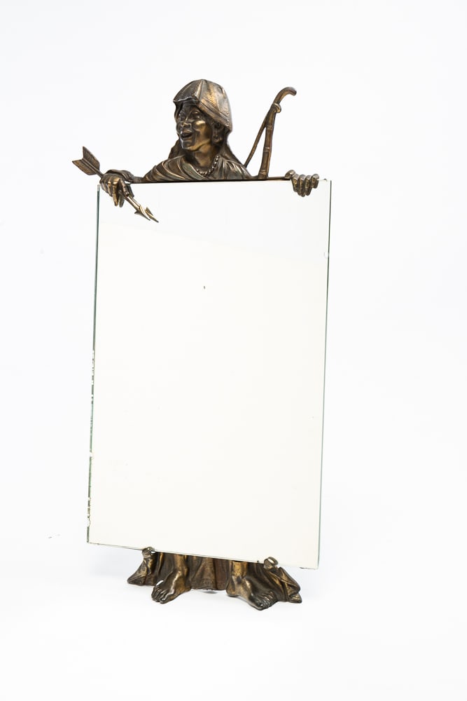 FIGURAL MIRROR.: American, circa 1900. Patinated cast metal frame of a robed gentleman wearing a keffiyeh holding the rectangular mirror. 24.5"h. 13.5"w.