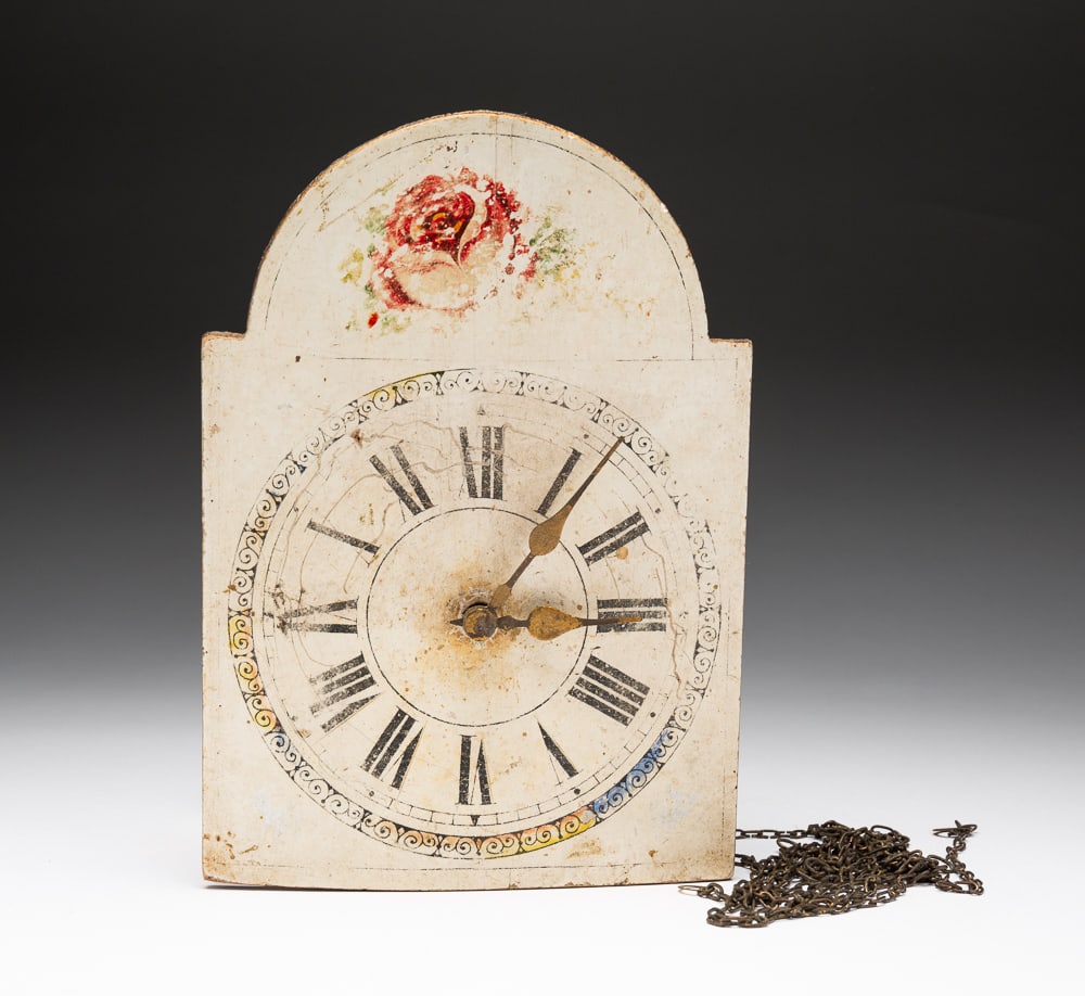 CHILD'S SIZE WAG ON THE WALL CLOCK.: German, mid-19th Century. Painted pine face with arched top and rose decoration. Brass works in pine case and missing weights and pendulum. Some paint wear and face is cupped. 10"h. 7"w.