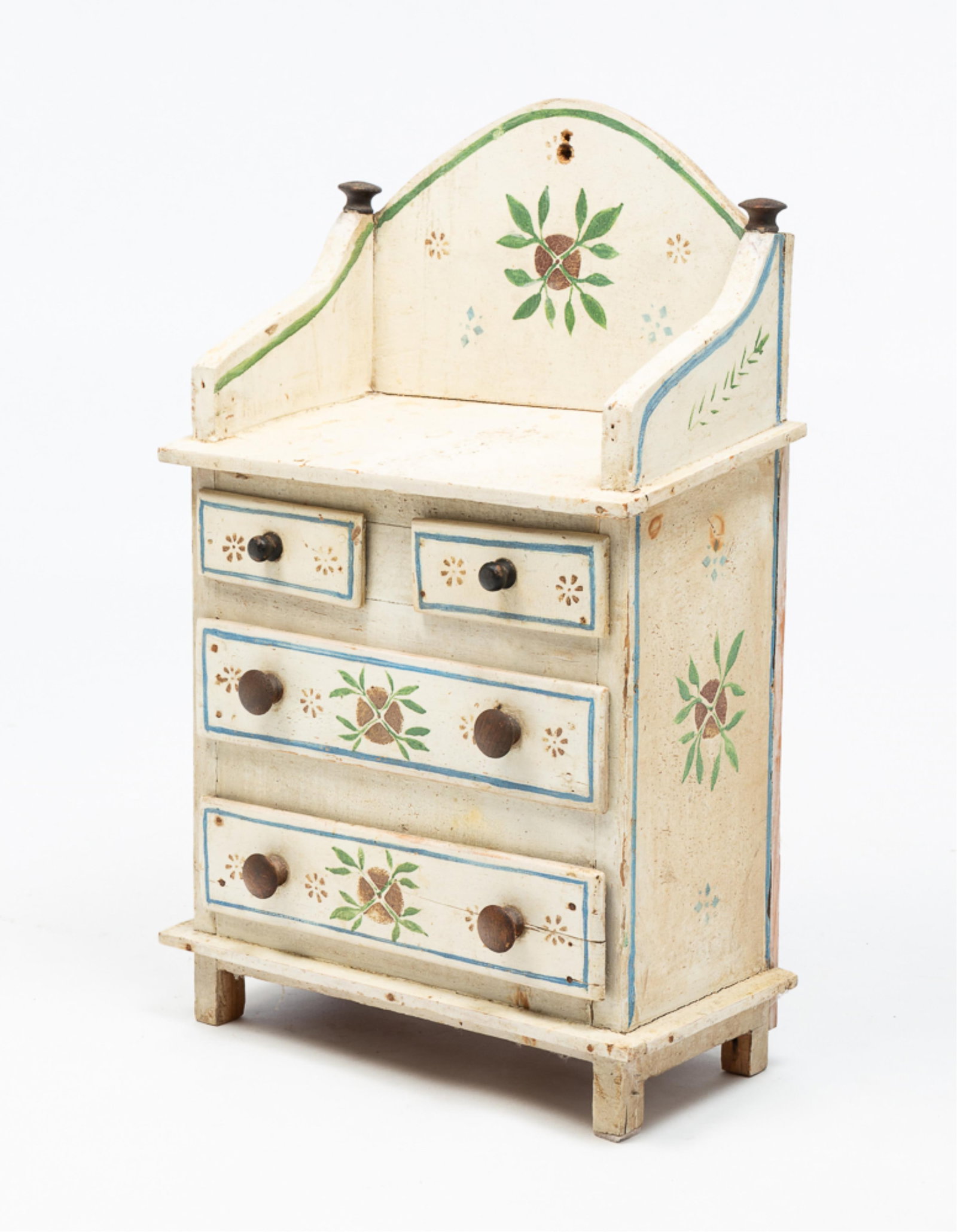 PAINTED AND DECORATED YOUTH SIZE CHEST.: American or European, late-19th Century. Pine. Arched gallery back with turned finials, solid ends, two overlapping drawers and rectangular legs. Worn white paint with blue and green pinstriping and f