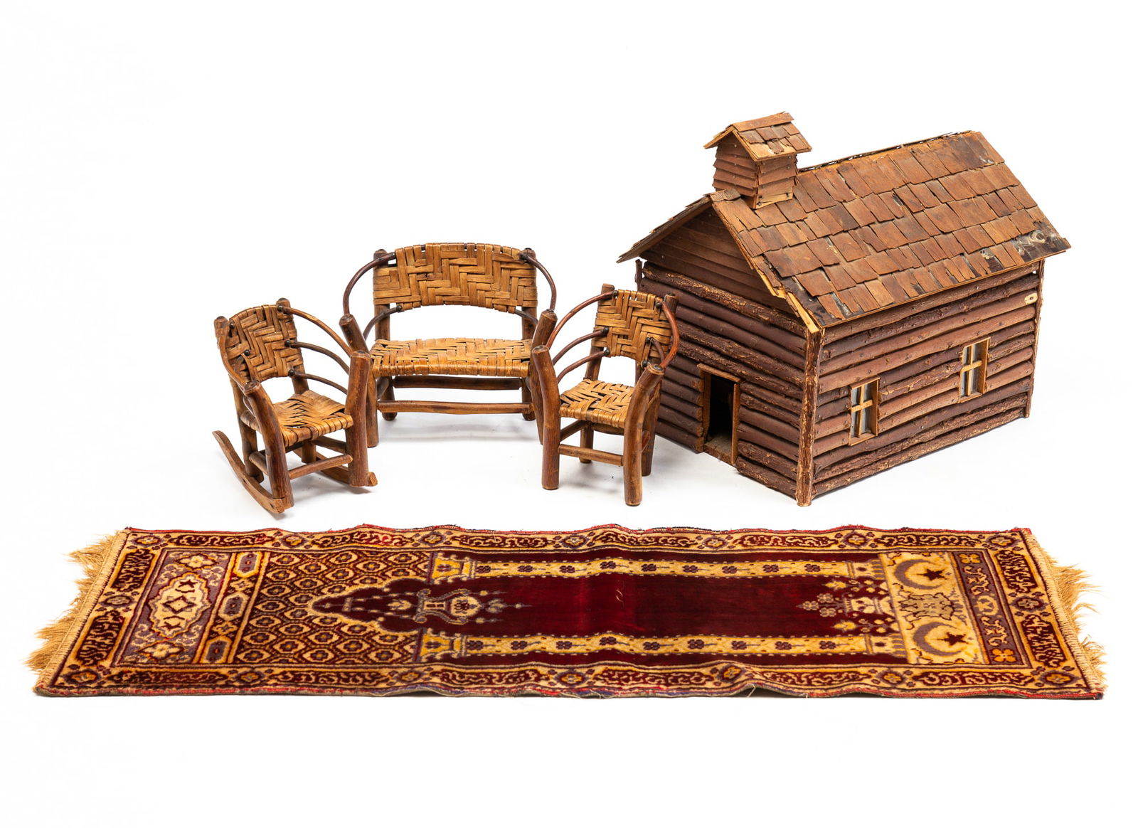 MINIATURE LOG CABIN CHURCH, FURNITURE, AND PRAYER RUG.: American, 20th Century. Primitve-style miniature model of a steepled church made from twigs, balsa wood, and wood veneers, the hinged door and top opening to reveal eight pews and a pulpit. With chips