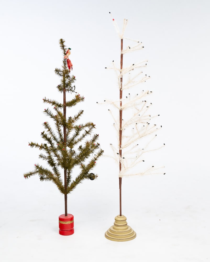 TWO FEATHER CHRISTMAS TREES.: German, fourth quarter 19th Century. Two feather trees with tissue paper wrapped bark. Green tree with red berries on some branches set into red painted wood cylinder. 43"h. White feather tree with bl