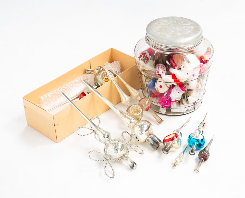 GLASS TREE TOPPERS AND FIGURAL CHRISTMAS BULBS.: Japanese, American and German, late-19th and early-20th Centuries. Ten glass spire Christmas tree toppers. And a glass jar full of figural Christmas tree lightbulbs. Including Santas, clowns, faces an