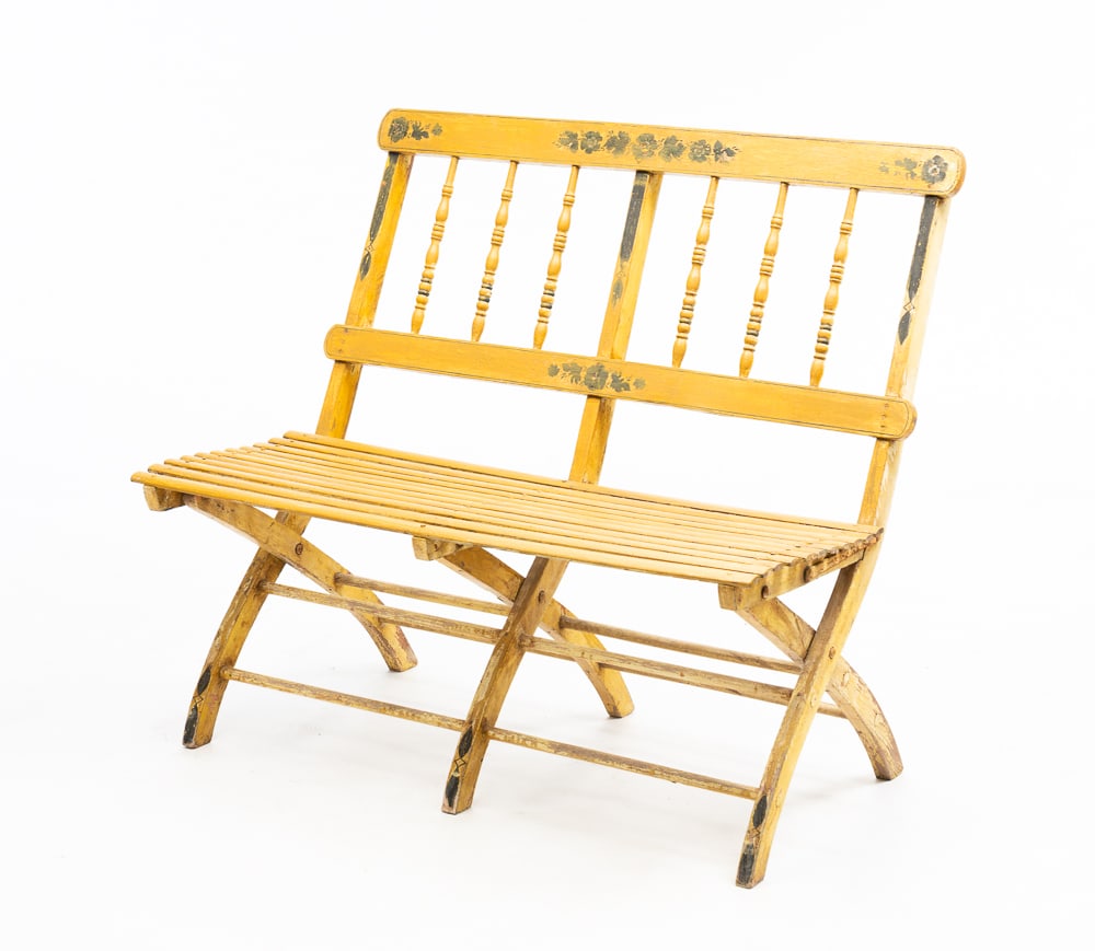 VICTORIAN PAINTED AND DECORATED FOLDING BENCH.: American, second half 19th Century. Mixed woods. Turned spindle back, slat seat and iron hardware. Worn yellow paint with floral decoration. Wear and loss. Seat 15"h. Overall 32"h. 35.75"w.