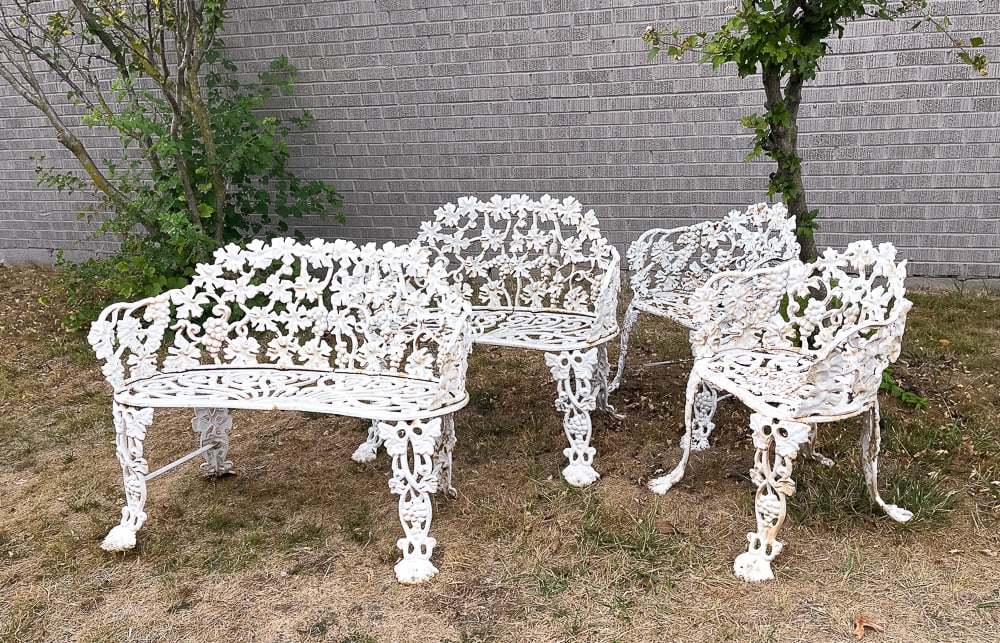 FOUR CAST IRON GARDEN SEATS.: American, mid-19th Century. Grape and vine pattern with worn layered white paint. Pair settees. Seat 14"h. Overall 28.5"h. 38.75"w. And a pair of armchairs, seat 14"h. Overall 26.5"h.
