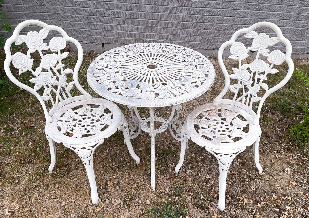 THREE PIECES OF GARDEN FURNITURE.: American, second half 20th Century. A pair of cast iron rose patterned chairs with worn white paint. Seat 16"h. Overall 32.5"h. And a small round aluminum rose pattern table. 25.5"h. 23.5"dia.