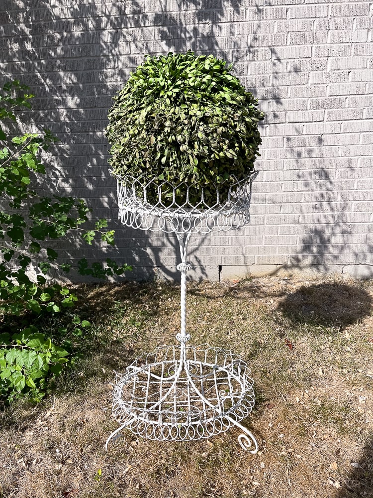 VICTORIAN STYLE WIRE GARDEN PLANTER.: American, 20th Century. Ornately woven with twisted iron center post and white paint. Includes a sphere of artificial greenery. 34.5"h.