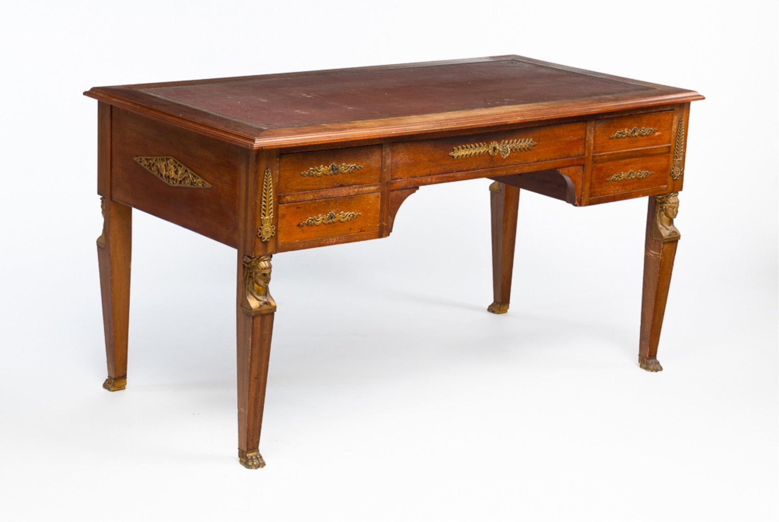 EGYPTIAN REVIVAL DESK.: European, mid-20th Century. Mahogany. Top with tooled leather insert, four dovetailed drawers, reverse with false drawer fronts, tapered legs and an Egyptian inspired foliate and figural ormolu. Some 