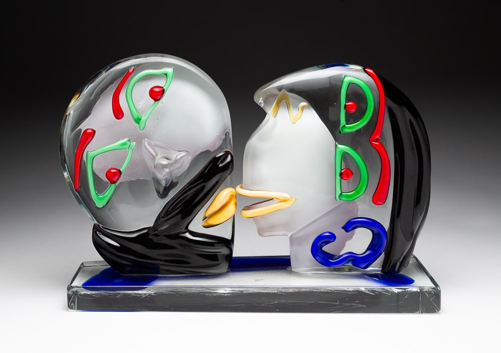 ABSTRACT GLASS SCULPTURE.: European, (possibly Murano, Italy), Contemporary. A couple kissing. Applied multi-colored featuresrectangular clear base with cobalt streaks. 10.75"h. 15.5"w. 5.25"d.