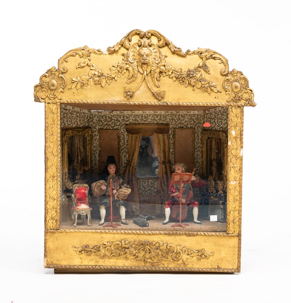 MUSICIAN'S AUTOMATON.: European, late-19th Century. Louis XV style. A violinist and cellist seated in a parlor. Case has fancy gesso gilded frame with wavy glass front. Some wear and loss and missing clock work music box an