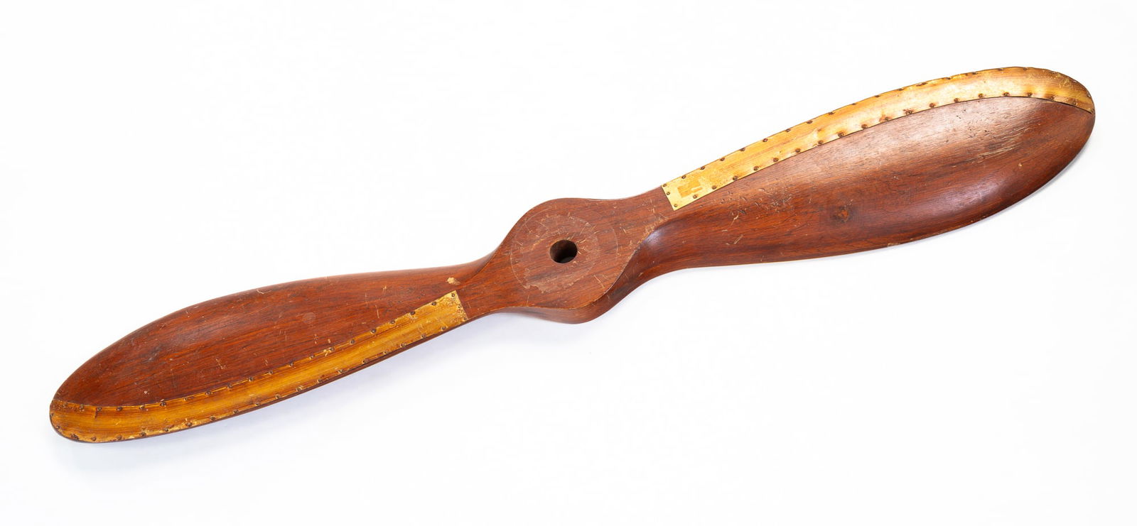 WOODEN AIRPLANE PROPELLER.: American, 20th Century. Carved wood with tacked brass. 39.5"w.