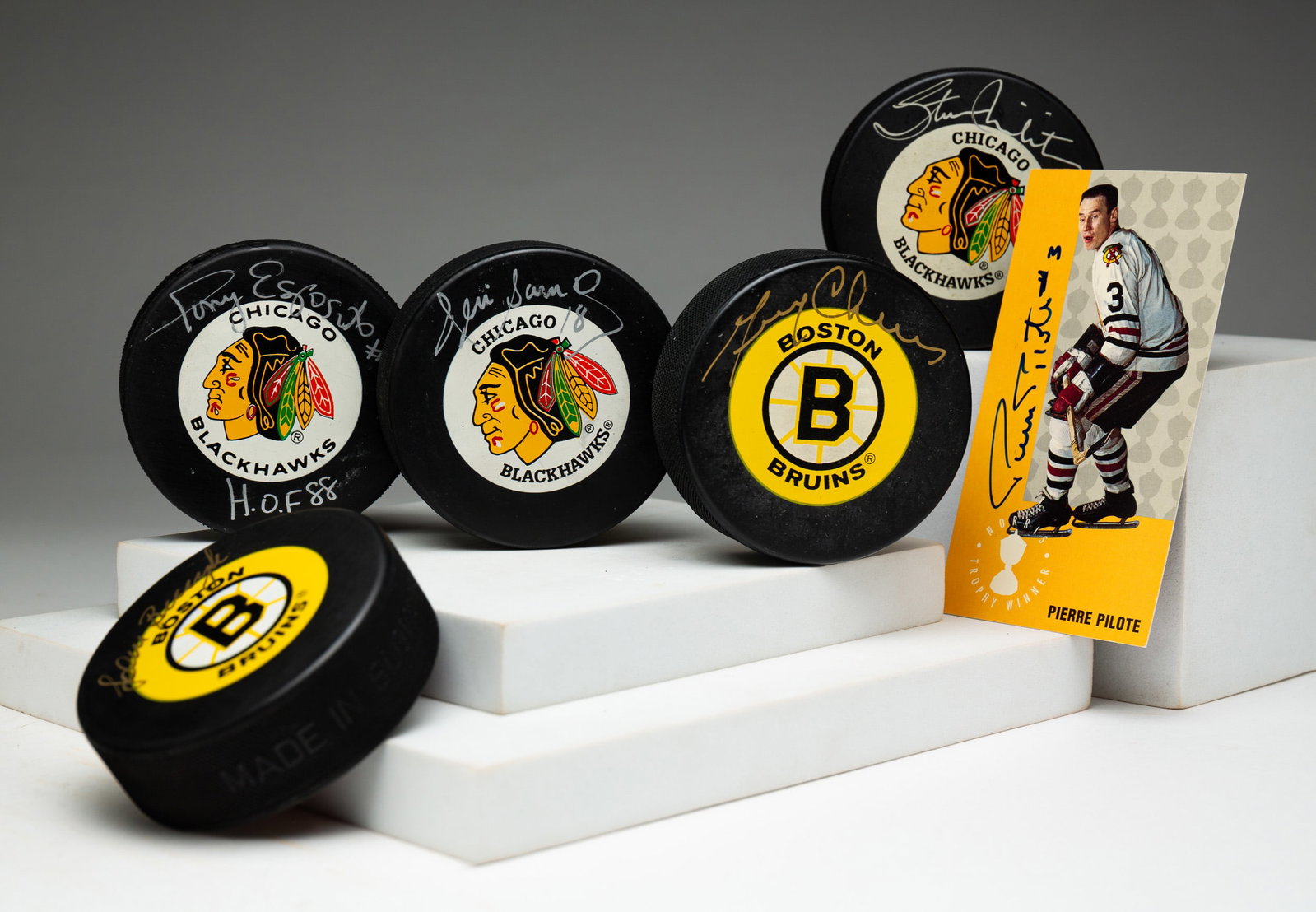 SIX PIECES AUTOGRAPHED HOCKEY MEMORABILIA.: American, 20th Century. Three Chicago Blackhawks pucks: Denis Savard, Tony Esposito and Stan Mikita. Two Boston Bruins pucks. Pierre Pilote autographed card, 4.75"h. 2.5"w. Ex. The Lifetime Sports Mem