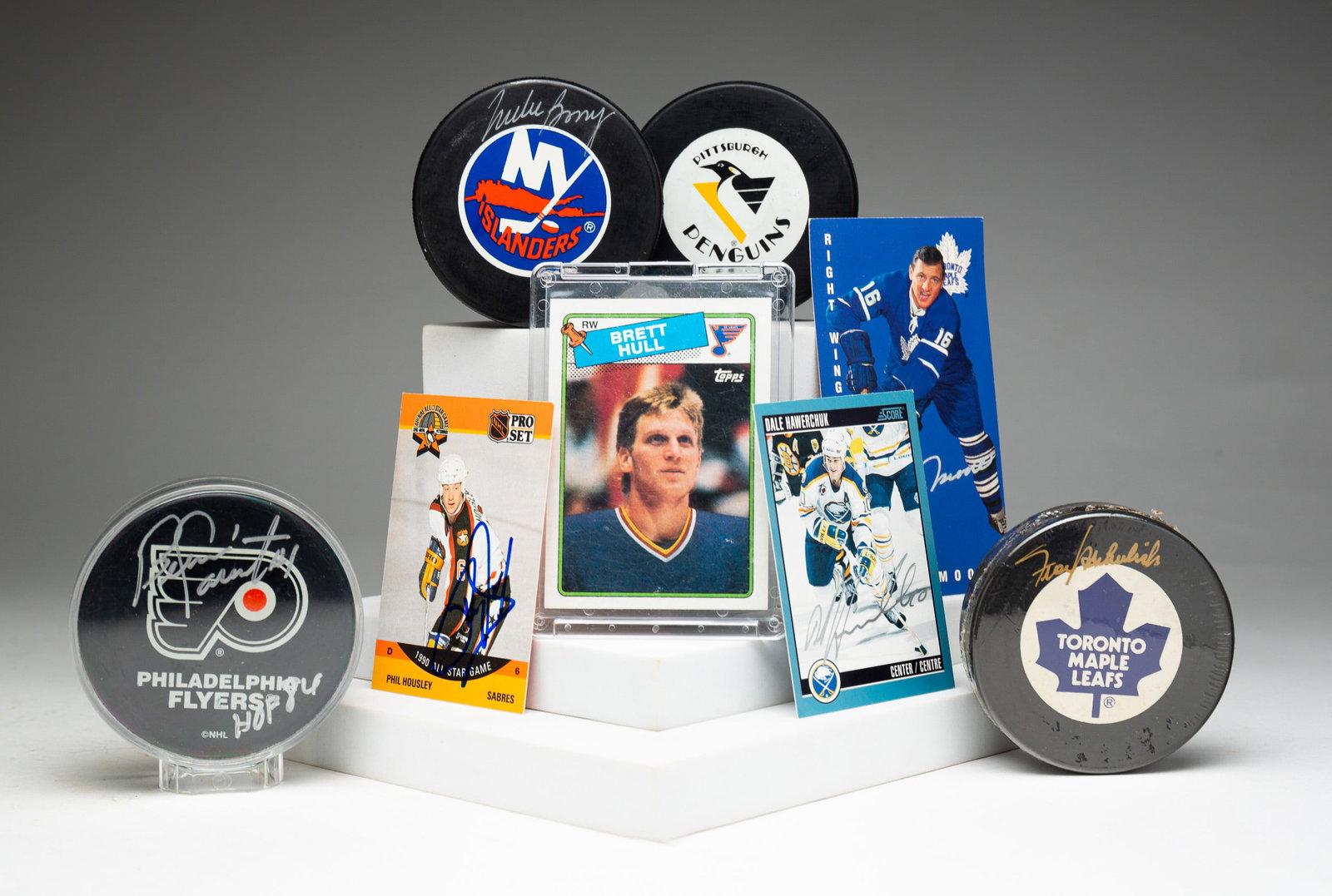 EIGHT PIECES OF AUTOGRAPHED HOCKEY MEMORABILIA.: American, 20th Century. Four trading cards: Dale Hawerchuk, Dickie Moore, Phil Housley and Brett Hull (not autographed). Four hockey pucks: Penguins (not autographed), Bernie Parent, Mike Bossy and Fr